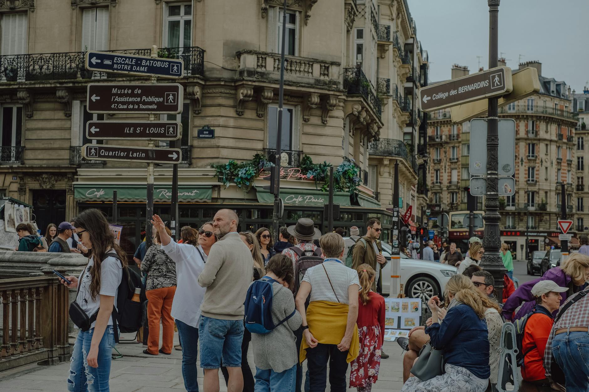 Busy street scene in Paris featuring diverse groups and iconic signage in the heart of the city.