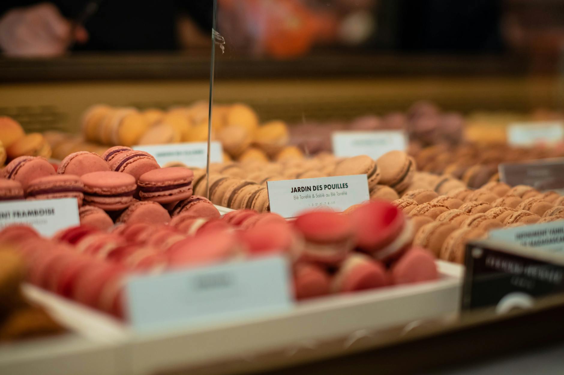 Vibrant macarons on display in a Paris market bakery, showcasing a variety of flavors.