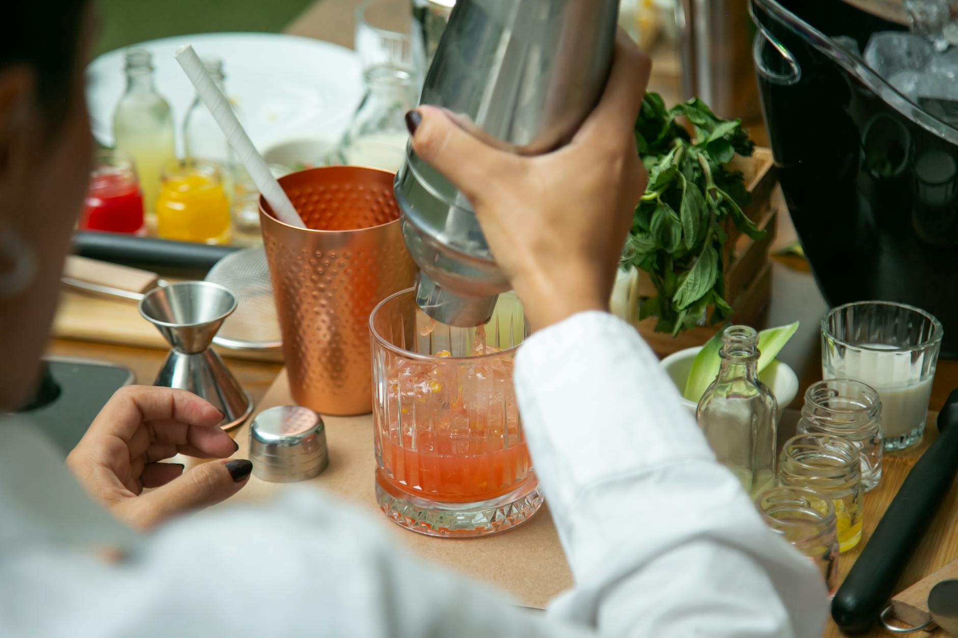 Close-up of hands mixing a cocktail with fresh ingredients at a bar in CDMX.