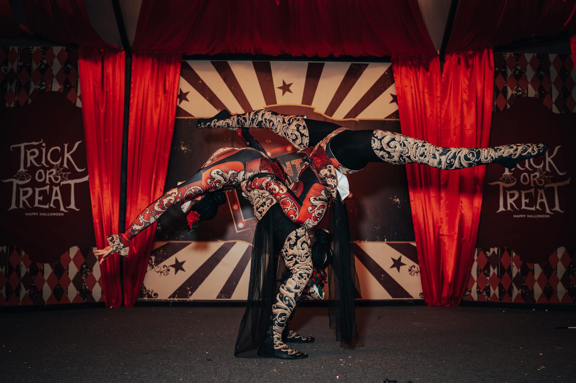 Acrobats in intricate costumes performing a Halloween-themed circus act indoors.